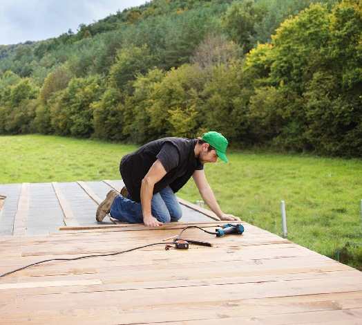 A man in black shirt and green hat on top of wooden deck.