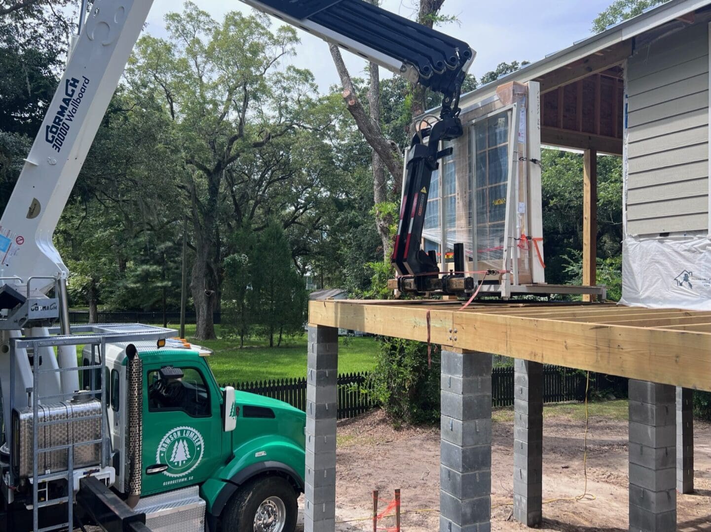 A crane is lifting a large window into the ground.